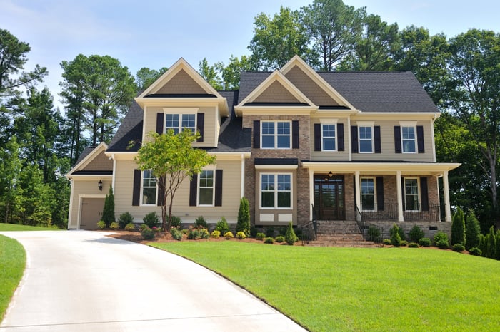 large brown brick home with siding set on green hill and surrounded by trees large brown brick home with siding set on green hill and surrounded by trees
