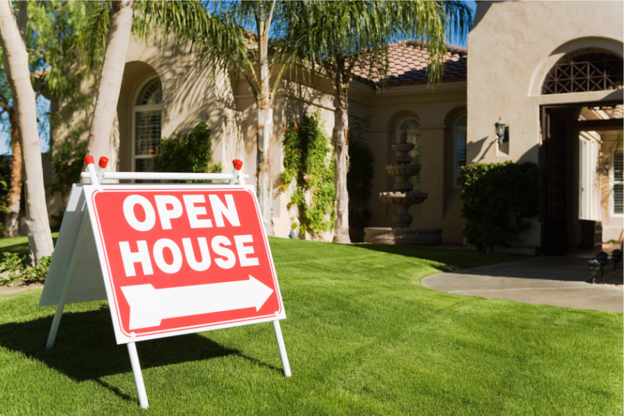green grass in front of tan home with red and white sign that says Open House